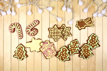 Tło świąteczne - malowane, kolorowe pierniki - choinka, prezent, bałwan, gwiazda -z lampkami na drewnianym blacie