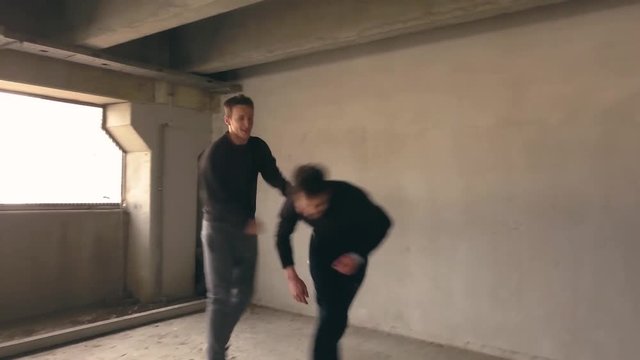 A man being attacked in a parking garage. Two men fighting as they punch and kick. Actors stage a hand to hand urban combat scene.