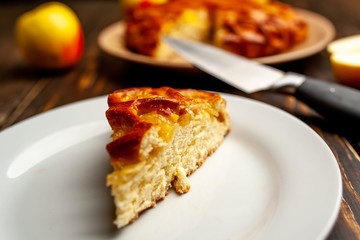 Fresh baked organic classic American apple pie with raisins, lying next to fruits, ingredients on wooden table. Country style