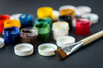 colorful paint gouache and brush on a black background.