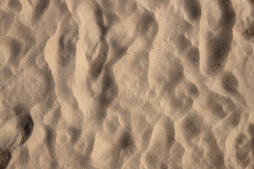 Beach sand with barefoot marks top view photo texture. Sea coast top view. Natural smooth sand texture.