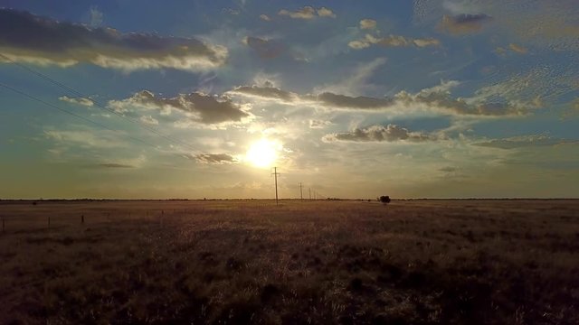 Drone shot moving forward, vast land of farm and agriculture with electric or telegraph poles and wire lines at sunset or sunrise