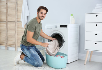 Young man using washing machine at home. Laundry day