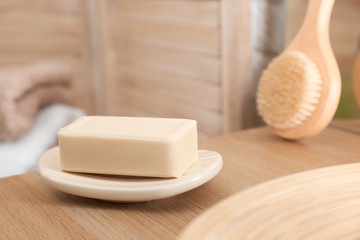 Dish with soap bar on wooden table. Space for text