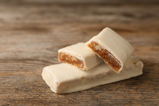 Tasty protein bars on wooden table. Space for text