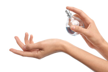 Young woman spraying perfume onto skin against white background, closeup