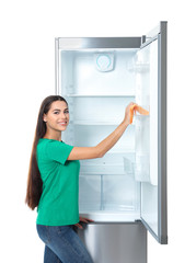 Young woman cleaning refrigerator with rag on white background