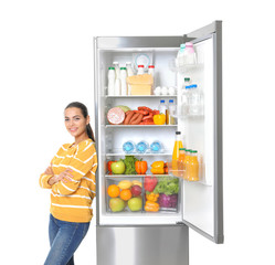 Young woman near open refrigerator on white background