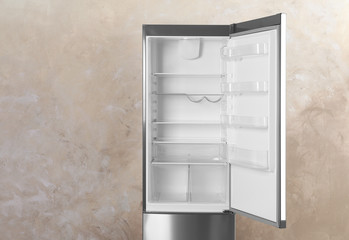 Open refrigerator with empty shelves on grey background. Space for text