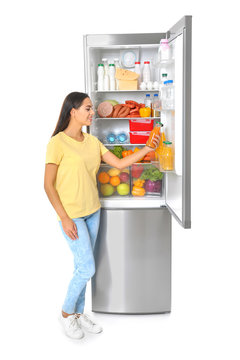 Young woman taking bottle of juice from refrigerator on white background