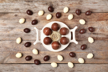 Flat lay composition with chocolate Easter eggs on wooden background