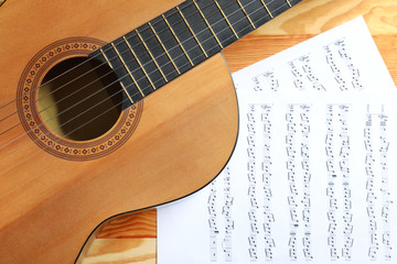 Fototapeta na wymiar Beautiful classical guitar and music sheets on wooden background, top view