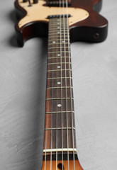 Modern electric guitar on color background, neck with strings in focus