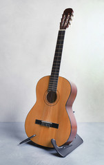 Fototapeta na wymiar Beautiful classical guitar on stand near color wall