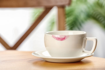 Ceramic cup with lipstick mark on table indoors. Space for text