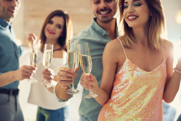 Friends clinking glasses with champagne at party indoors