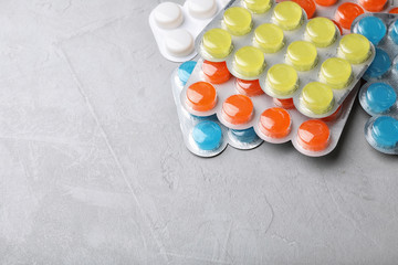 Blisters with color cough drops on grey background. Space for text