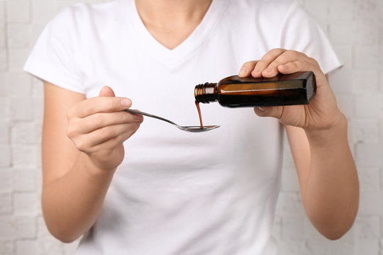 Woman pouring cough syrup into spoon, closeup