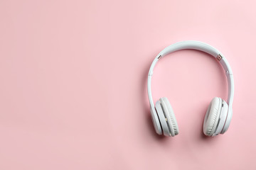 Wireless headphones on color background, top view. Space for text