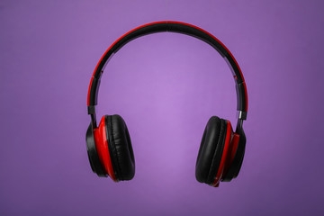 Wireless headphones with earmuffs on color background