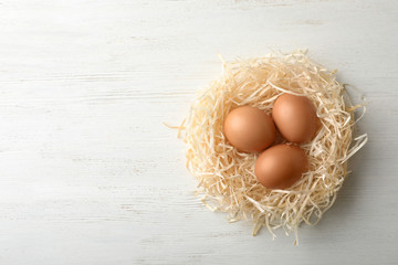 Nest with eggs and space for text on wooden background, top view. Pension concept