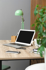 Stylish workplace interior with laptop on table near wooden wall. Space for text