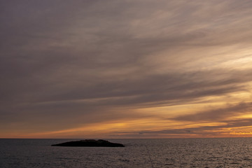 Naklejka na ściany i meble Sunset over the Mediterranean through cloudy winter skies