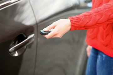 Closeup view of woman opening car door with remote key