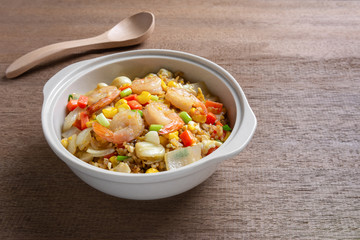 fried rice with shrimp in a ceramic bowl on wooden table. homemade style food concept.