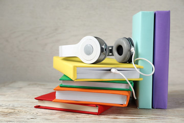 Modern headphones with hardcover books on wooden table