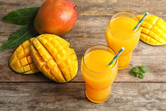 Fresh tropical mango juice and fruits on wooden table