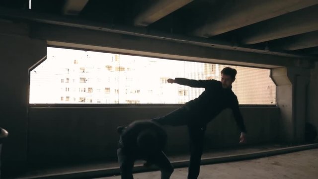 Martial arts being used during a fight. Kicking, punching and blocking the blows of an attacker. Self defense. Mugger in a parking deck assaulting a victim. Stunt men act out a fight scene.