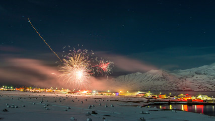 New years fireworks over town of Hauganes, Iceland