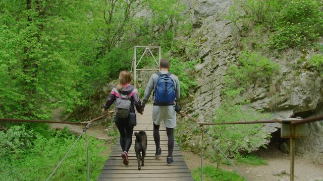 Hikers With Dog Walking On A Bridge