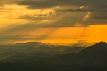 Fototapeta na wymiar landscape sunrise on hill mountain with rays of sunlight shining on the cloud yellow sky