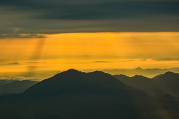 landscape sunrise on hill mountain with rays of sunlight shining on the cloud yellow sky