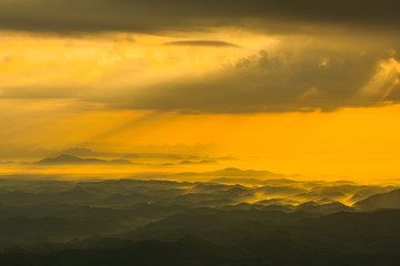 Obraz premium landscape sunrise on hill mountain with rays of sunlight shining on the cloud yellow sky