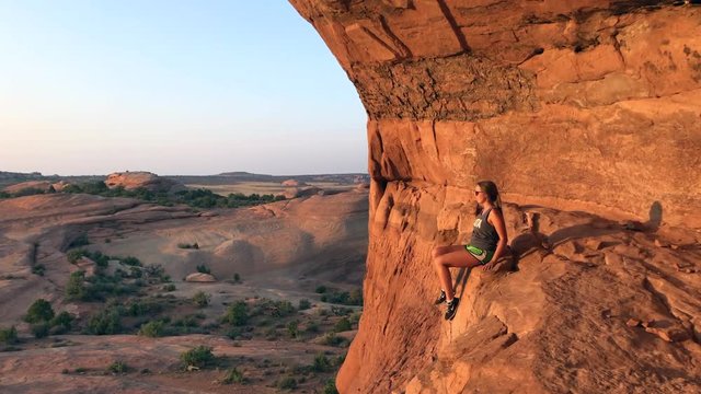 Woman Resting On Rock From Free Climbing In Desert Of Utah At Sunset