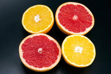 cut pieces of different citrus fruits on dark background