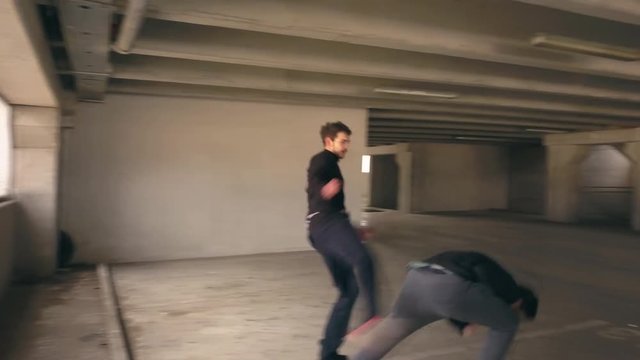Man uses karate to subdue a foe. Two men in hand to hand combat in a city parking garage. Self defense to fend of an attacker. Actors in a fight sequence.