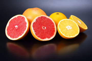Cut fresh oranges and grapefruits on a dark background