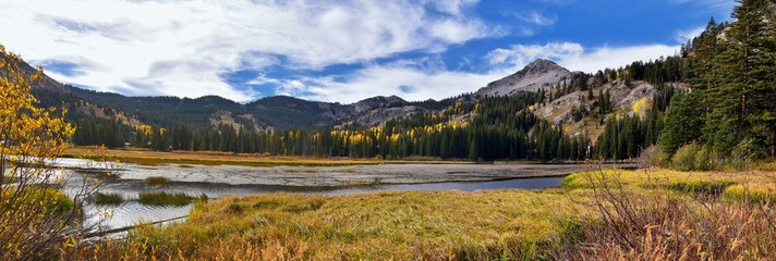 Silver Lake by Solitude and Brighton Ski resort in Big Cottonwood Canyon. Panoramic Views from the hiking and boardwalk trails of the surrounding mountains, aspen and pine trees in brilliant fall autu