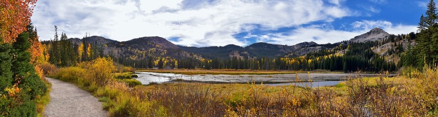 Silver Lake by Solitude and Brighton Ski resort in Big Cottonwood Canyon. Panoramic Views from the hiking and boardwalk trails of the surrounding mountains, aspen and pine trees in brilliant fall autu