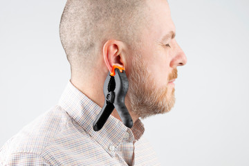 Large clothespin hanging on the ear of a bearded man