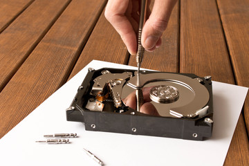 Hands of a man with a screwdriver disassembling the hard drive