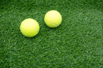 Two tennis balls are on green grass