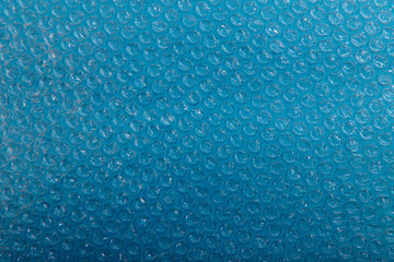 Abstract bubbled polyethylene texture background on light blue paper surface. Cropped shot,...