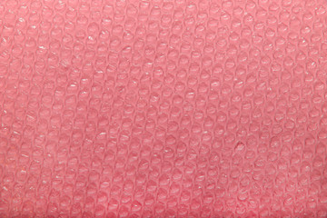 Abstract bubble polyethylene texture background on pink paper surface. Cropped shot, horizontal, blurred, polyethylene concept,