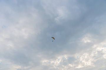 Fototapeta na wymiar Tandem motor paraglider flying high in the evening cloudy sky with a pilot and a passenger.
