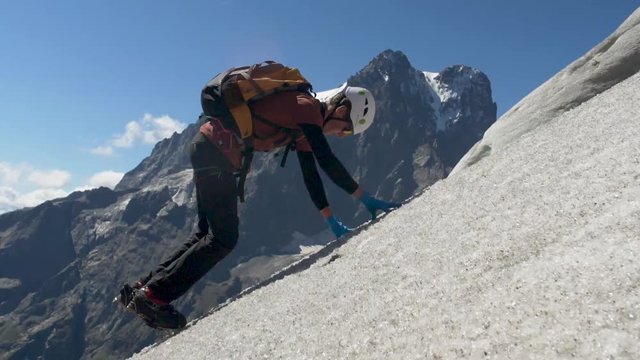 young man climbing up gletsjer with his gear in slow-motion